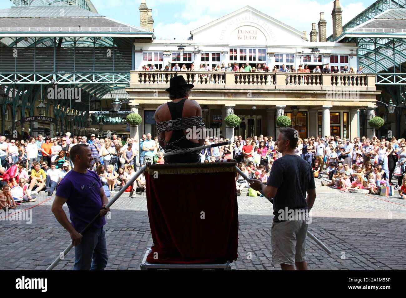 Authentic imagery in Covent Garden, London. The street Entertainer has the attention of the people including the patrons of the Punch and Judy pub on the terrace. Stock Photo