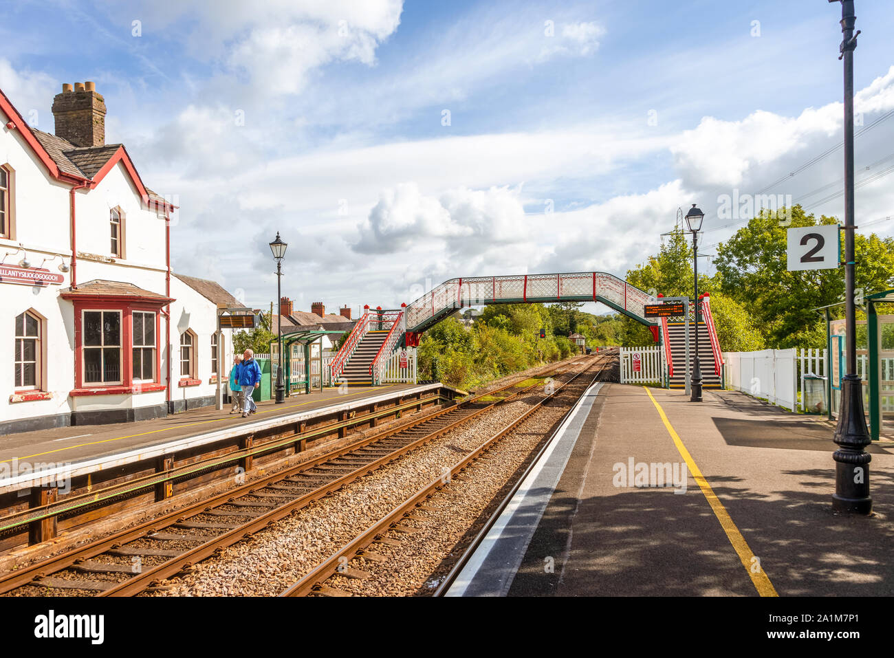 Station building and footbridge at  Llanfairpwllgwyngyll, in Wales known to have the longest place name in the UK. A blue sky is overhead. Stock Photo