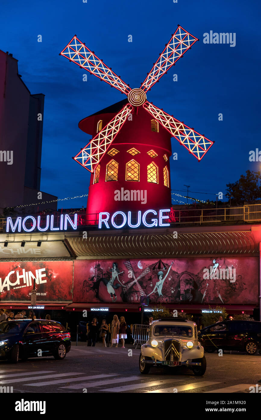 The Moulin Rouge in Paris, France at night with classic Citroen Traction 11CV vintage car in the foreground. Stock Photo