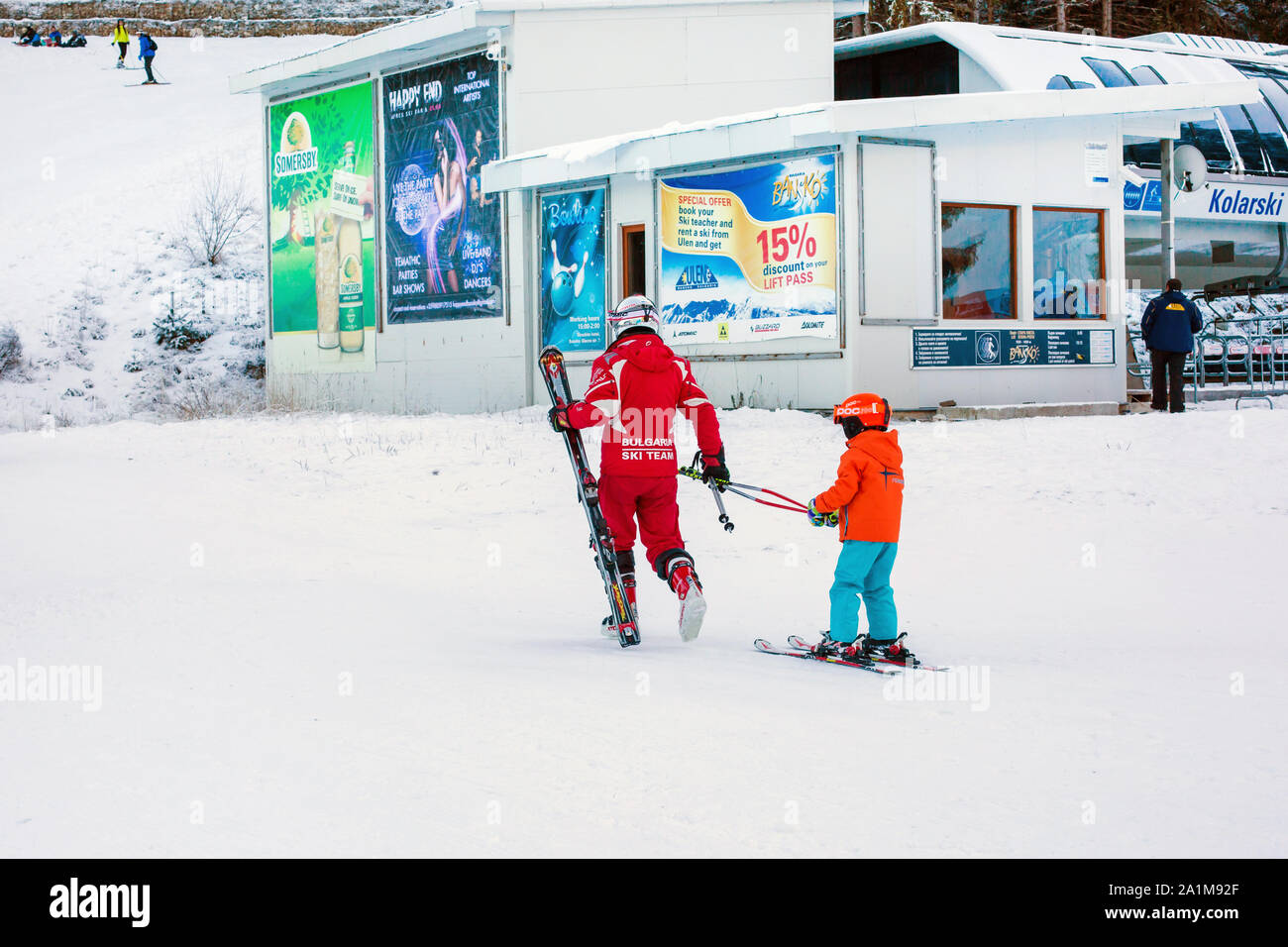 Bansko, Bulgaria - December, 12, 2015: The small child learning to ski and ski instructor on the slope in Bansko, Bulgaria Stock Photo