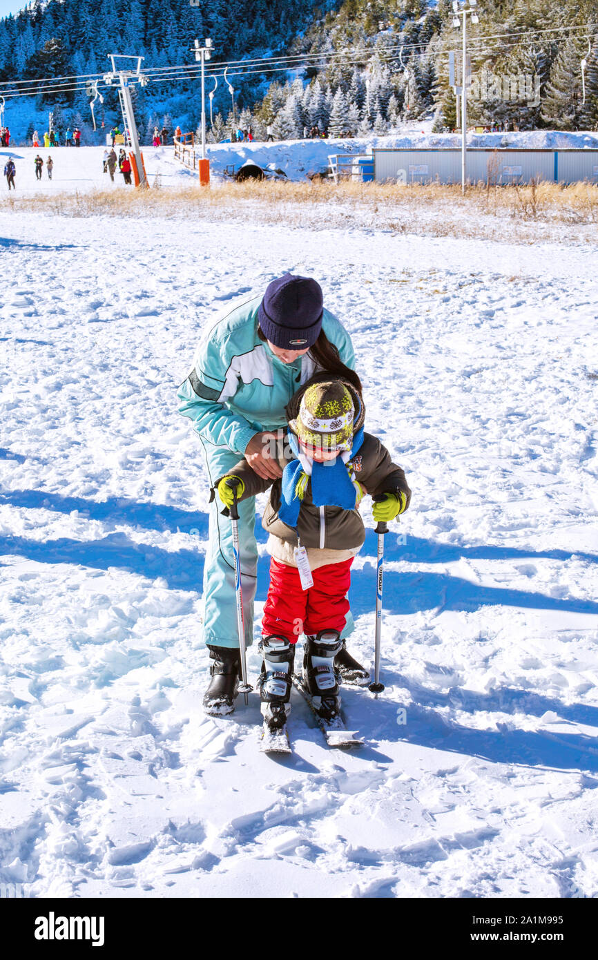 Bansko, Bulgaria - December, 12, 2015: The small child learning to ski with mother on the slope in Bansko, Bulgaria Stock Photo