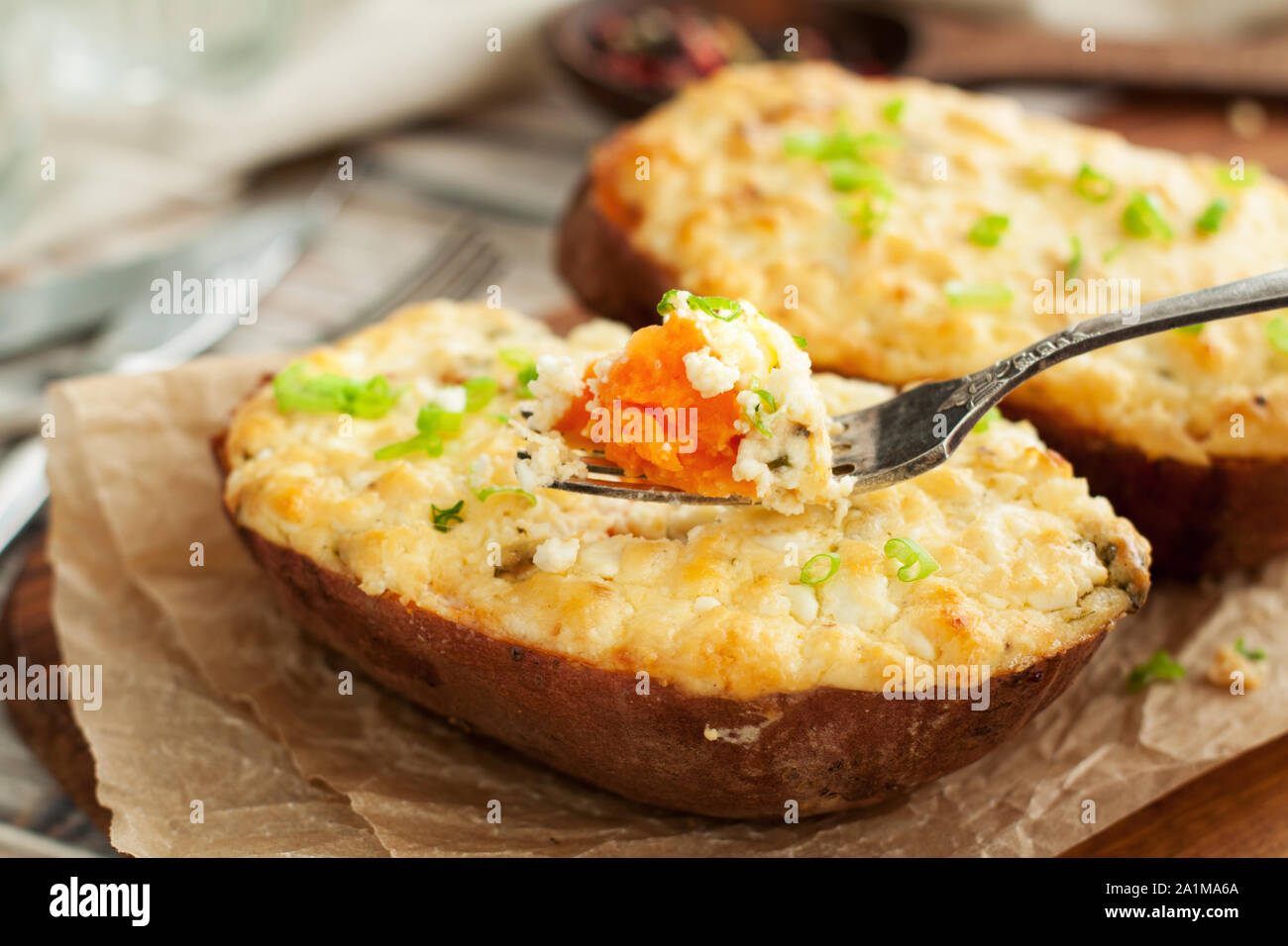 Backed sweet potatoes stuffed with eggs, cheeese and herbs on wooden cutting board Stock Photo