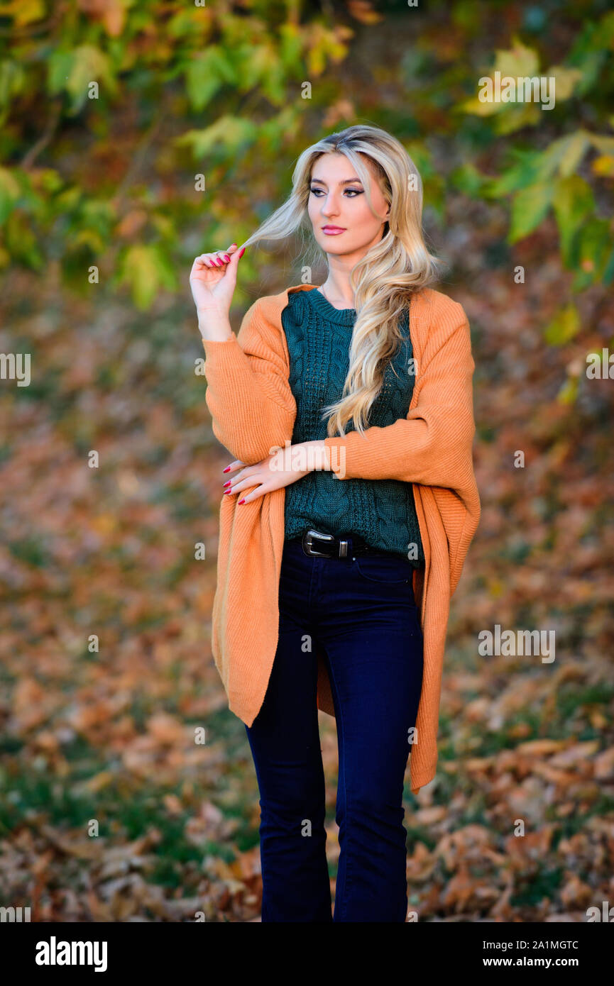 Cozy outfit ideas for weekend. Woman walk sunset light. Clothing for every  day. Cozy casual outfits for fall. Girl adorable blonde posing in warm and  cozy outfit autumn nature background defocused Stock
