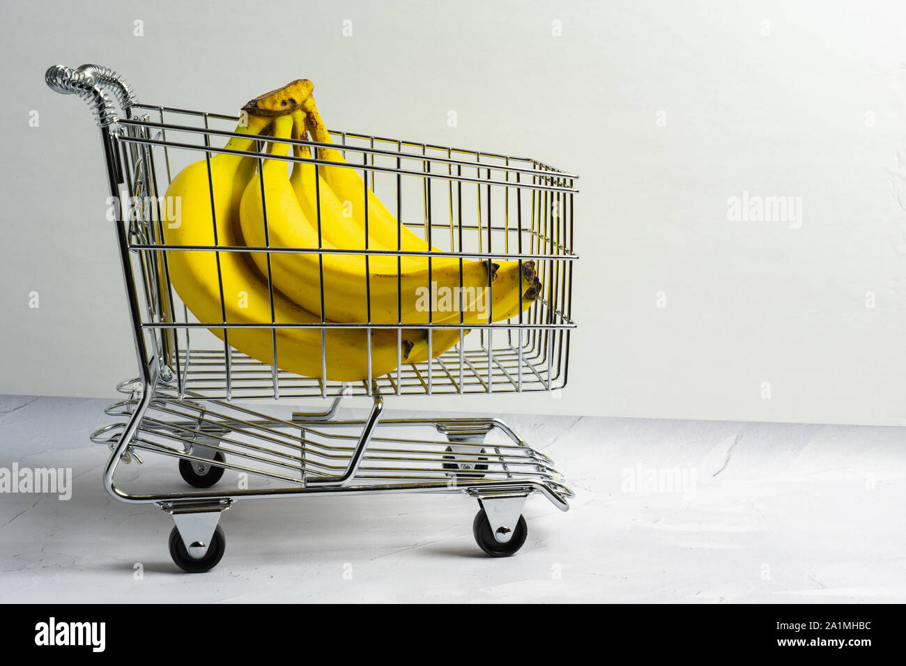 bunch of yellow bananas in a shopping cart on a neutral background with