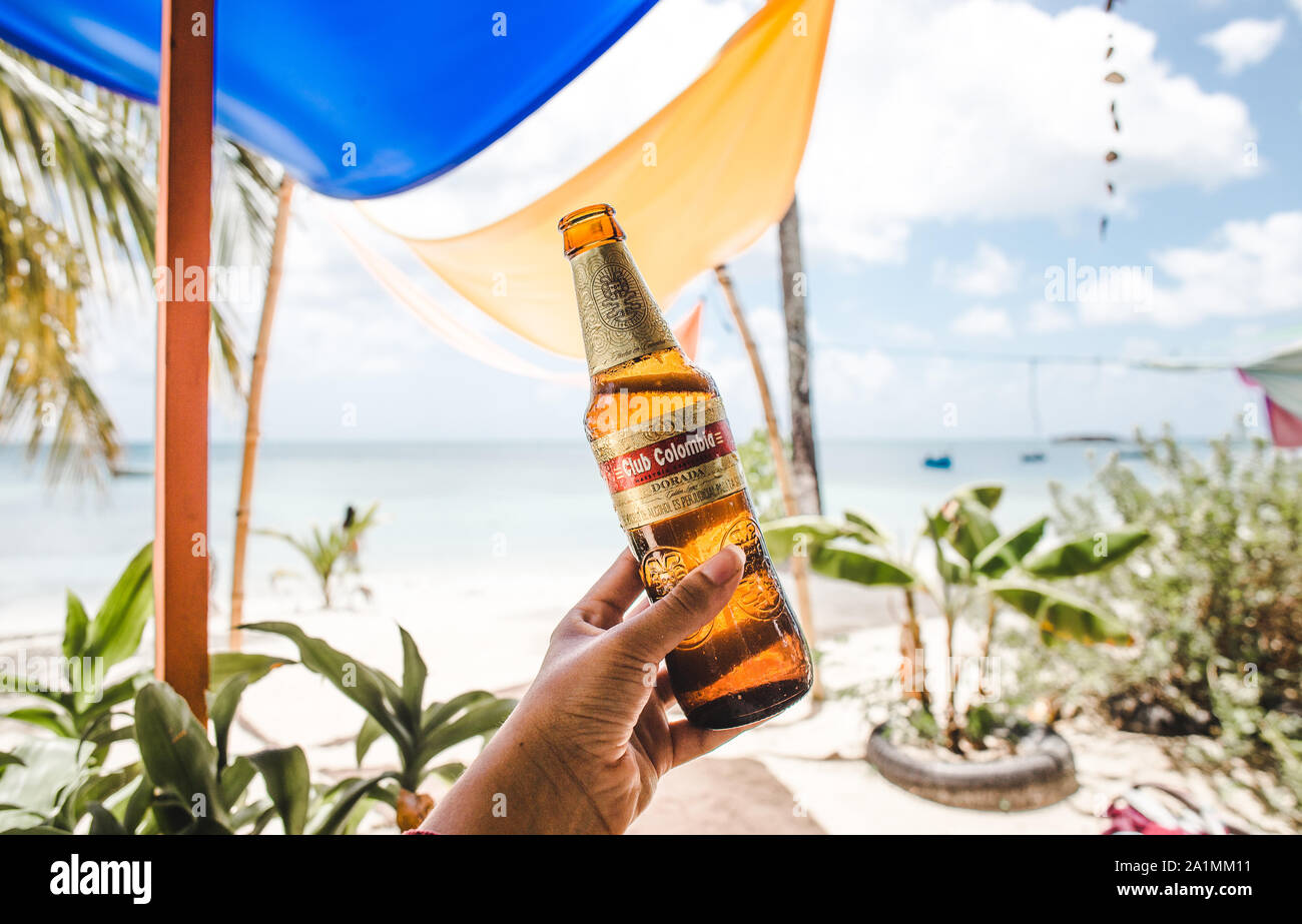 hand holding up a refreshingly cold bottle of Club Colombia - the premium national beer of Colombia - at a beach on a Caribbean island Stock Photo