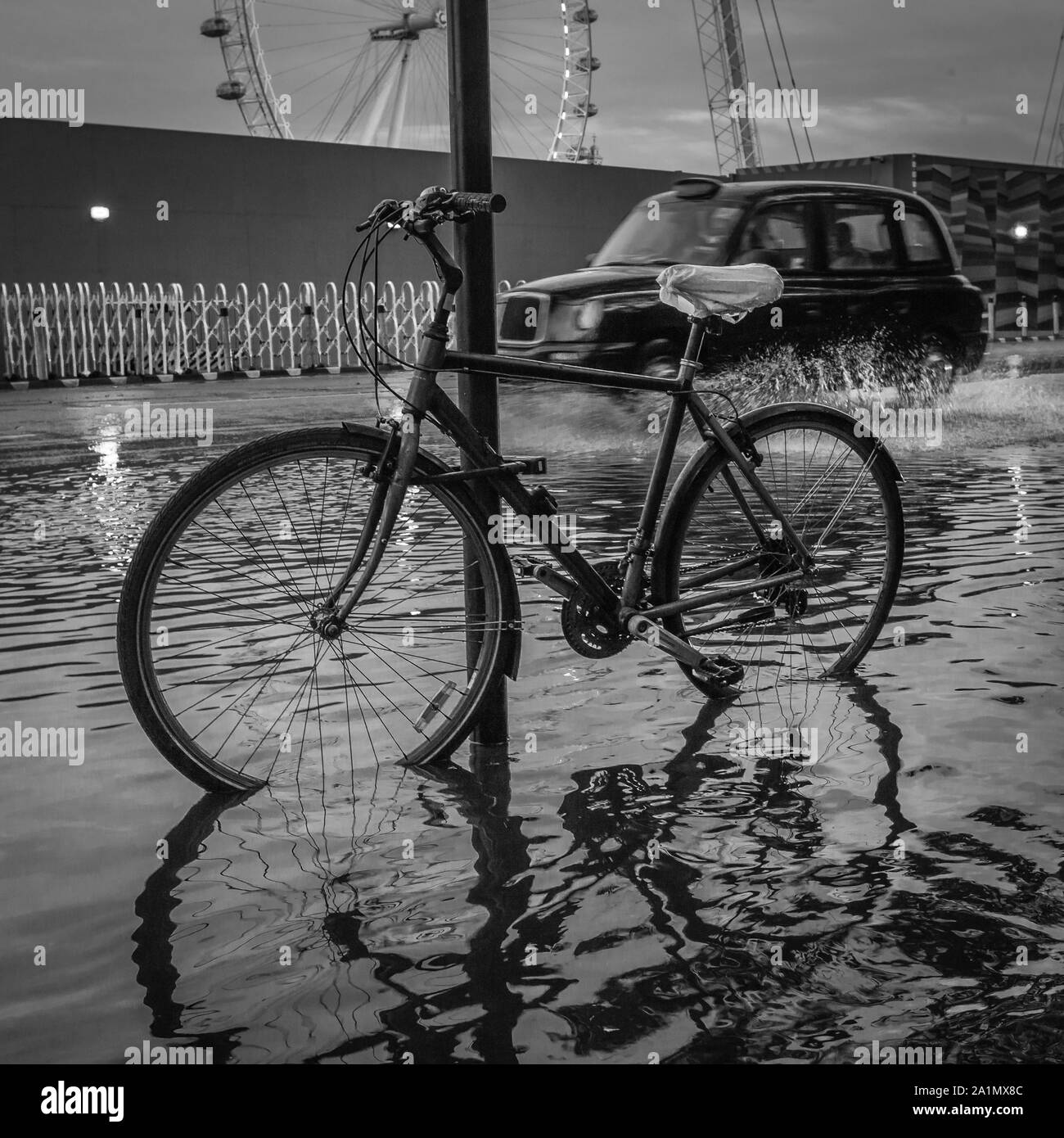 An iconic London black cab splashes through flood water following heavy rain in London. Stock Photo