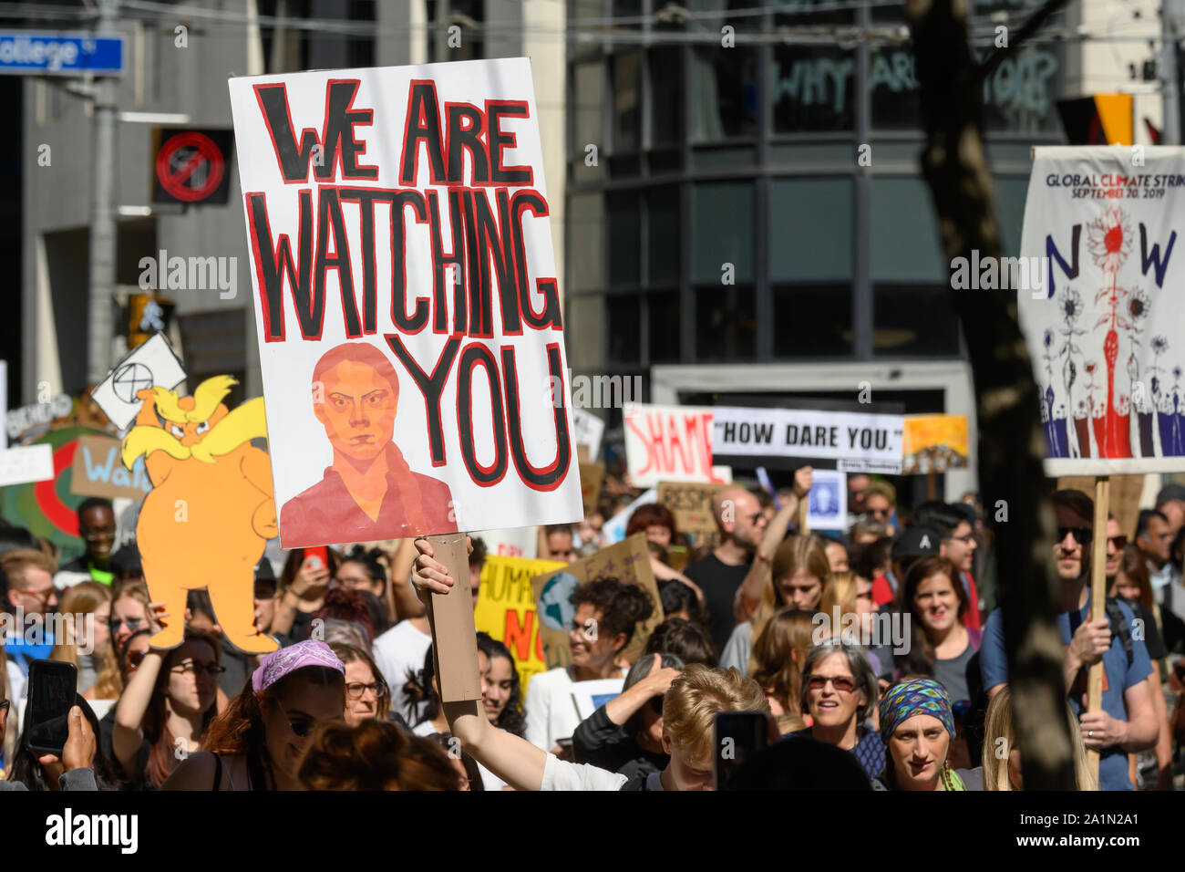 A demonstrator marches with a sign featuring Greta Thunberg during the Toronto Climate Strike with her 'How Dare You' quote visible on another sign. Stock Photo