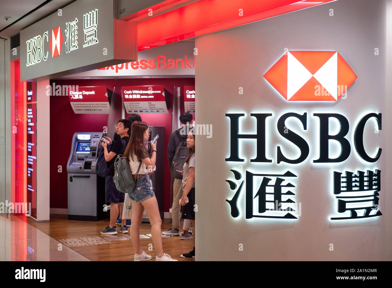 Commuters withdraw money from British multinational banking HSBC ATM