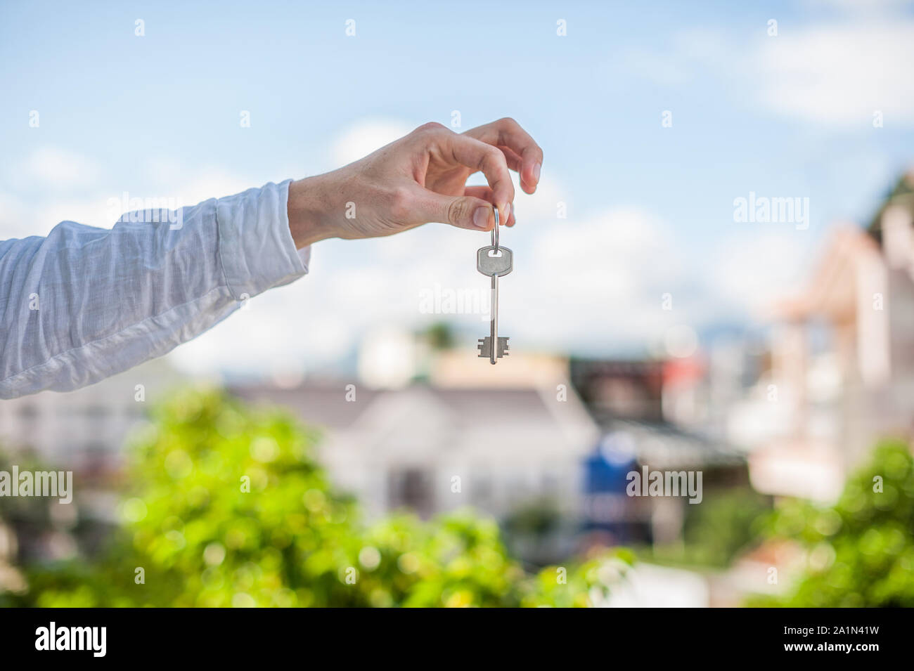 man holding key to the house on background of houses in the city. Deal ...