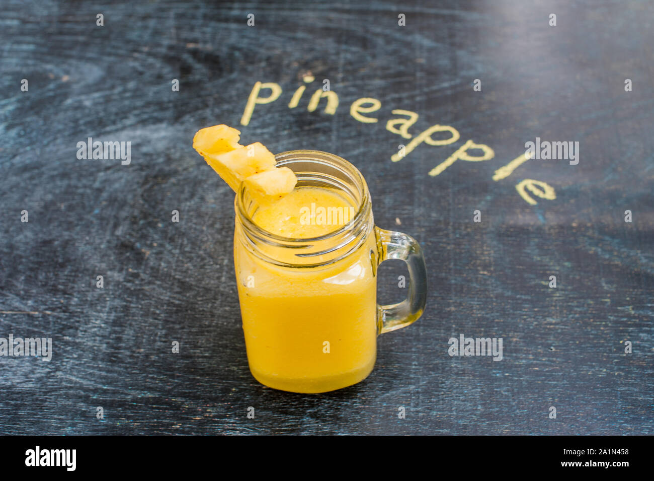 Pineapple cocktail with a slice of on wooden background and inscription in chalk . Tropical concept Stock Photo