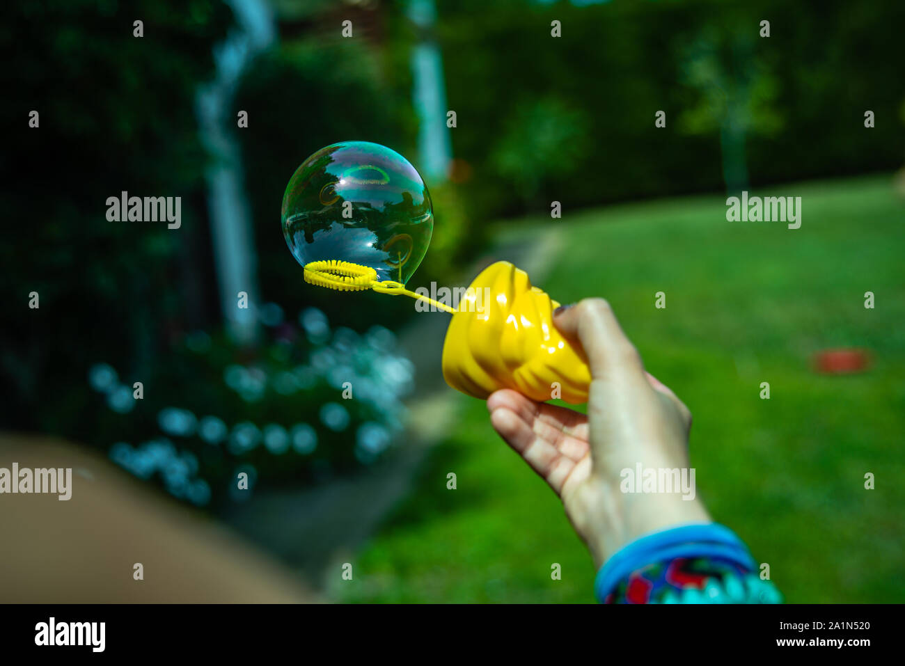 Little girl playing soap bubbles in the backyard in the sun Stock Photo ...