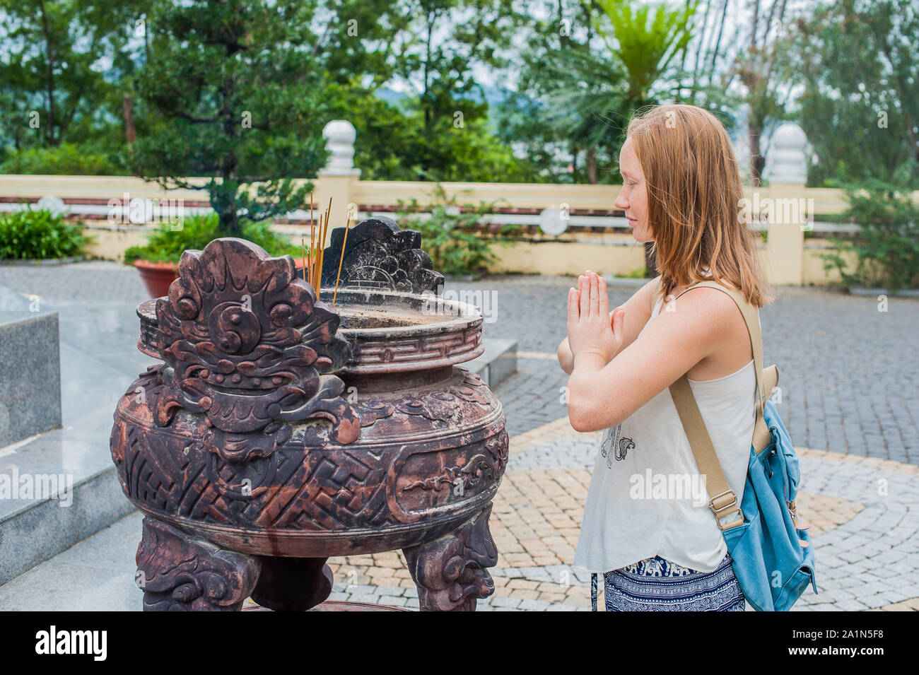 Young Woman Traveler Praying In Polite Action With Incense Sticks At 