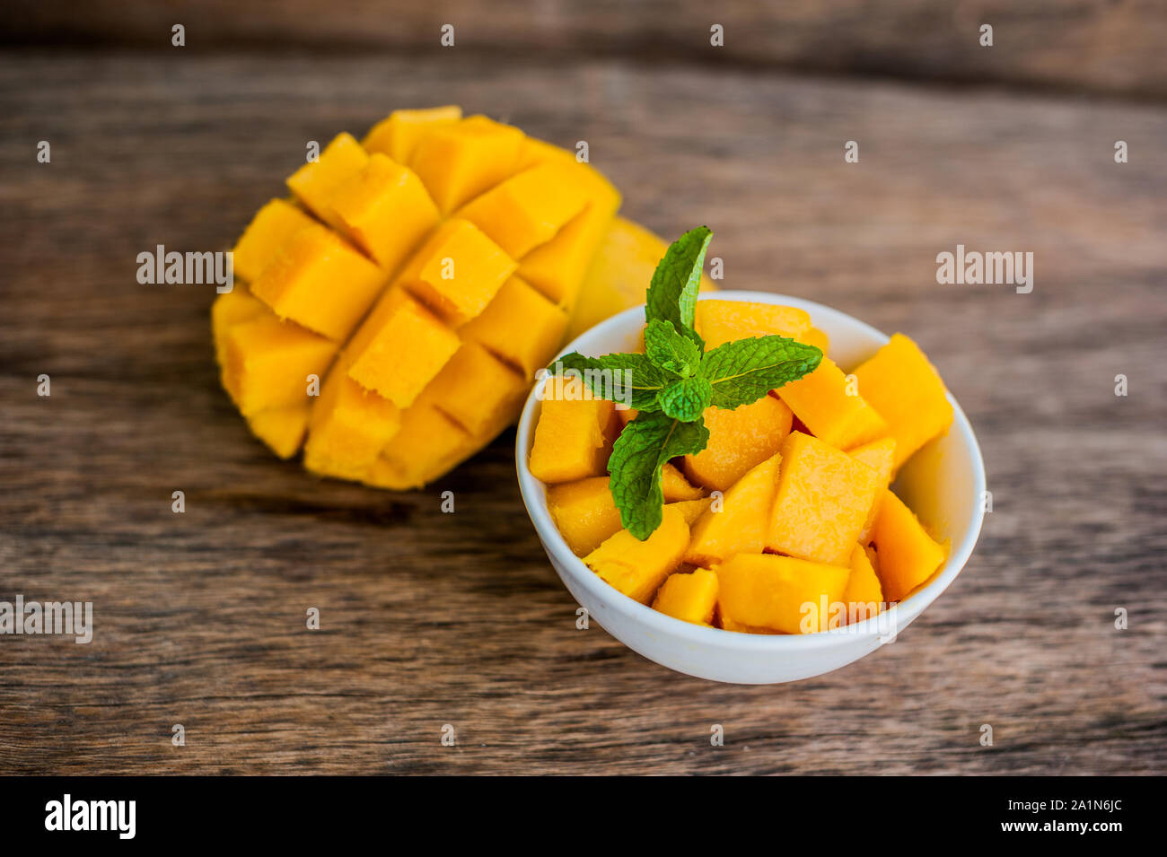 Mango fruit and mango cubes on the wooden table. Stock Photo