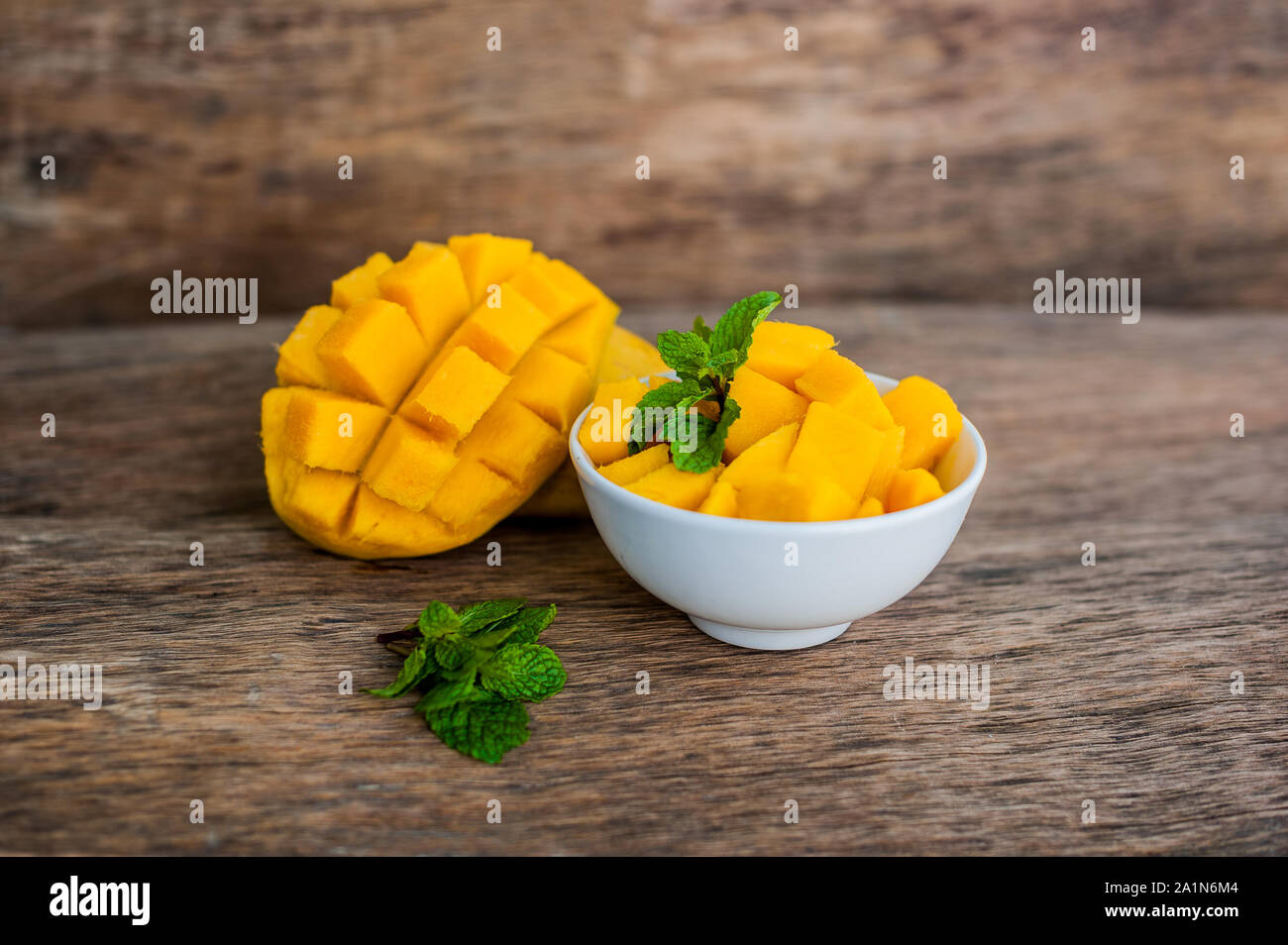 Mango fruit and mango cubes on the wooden table. Stock Photo