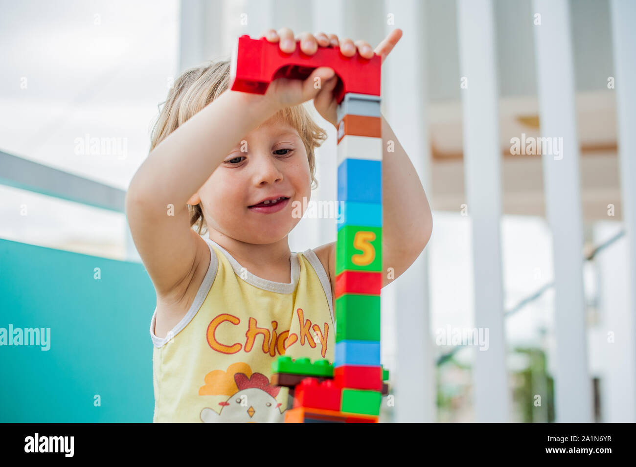 Cute little kid boy playing with lots of colorful plastic blocks indoor ...