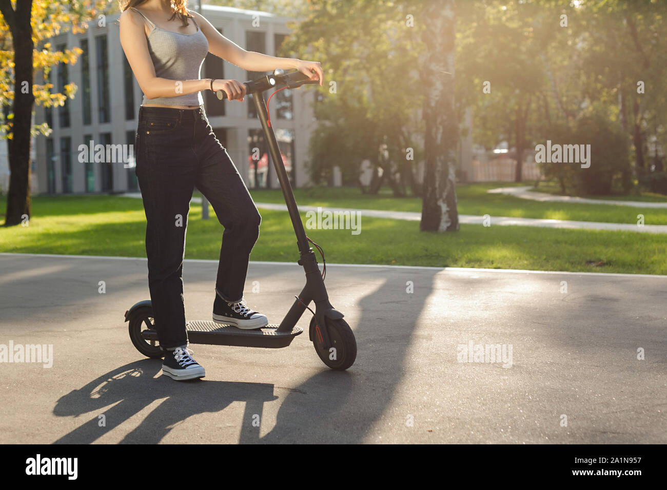 girl riding an ecofriendly electric kick scooter in a park in