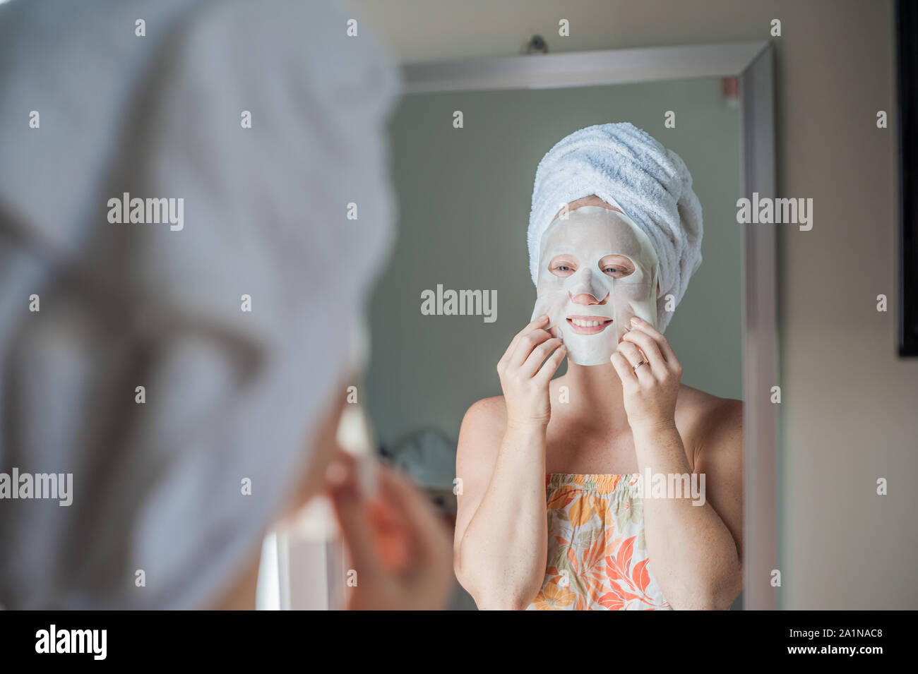 Young red-haired woman doing facial mask sheet Stock Photo - Alamy