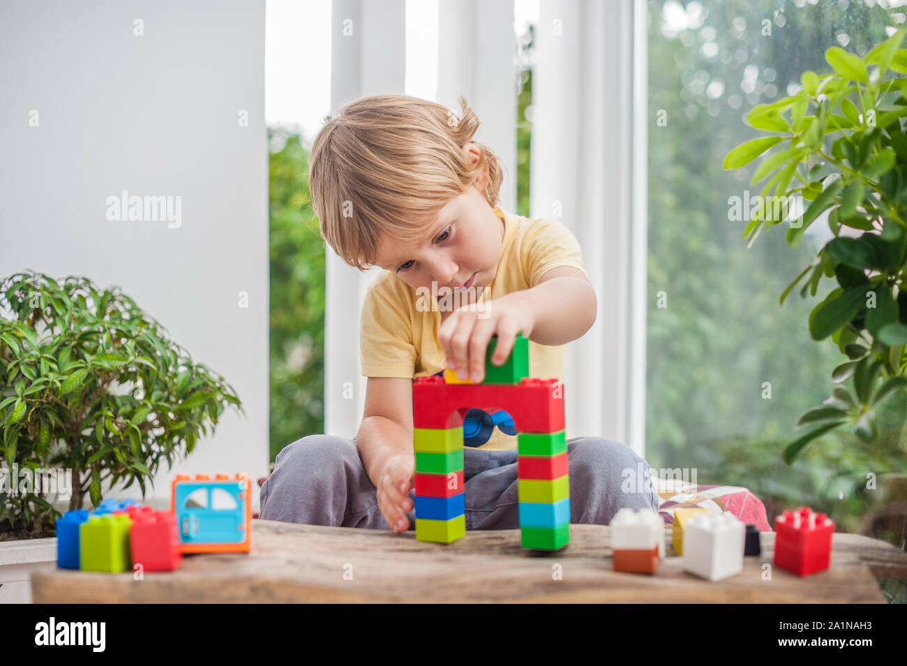 Cute little kid boy with playing with lots of colorful plastic blocks ...