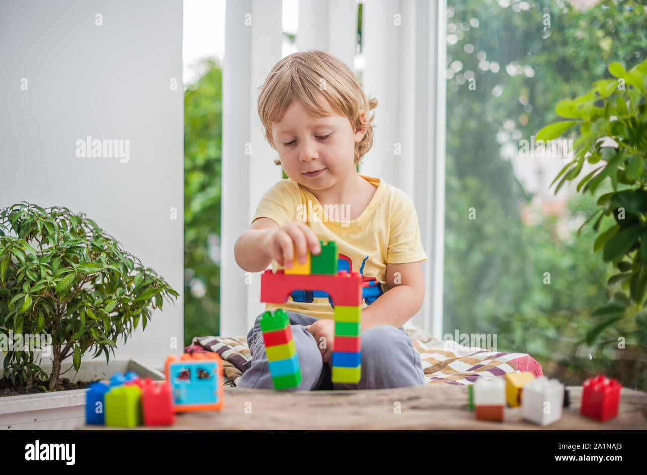 Cute little kid boy with playing with lots of colorful plastic blocks ...