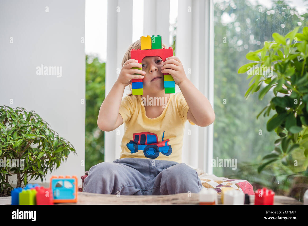 Cute little kid boy with playing with lots of colorful plastic blocks ...