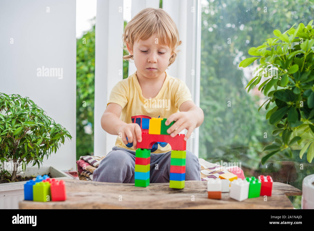Cute little kid boy with playing with lots of colorful plastic blocks ...