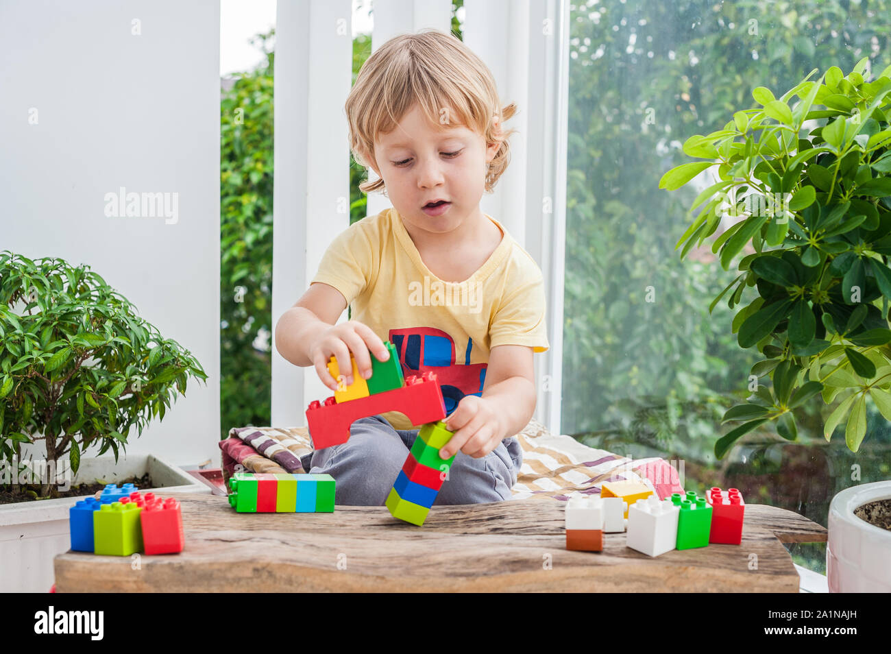 Cute little kid boy with playing with lots of colorful plastic blocks ...