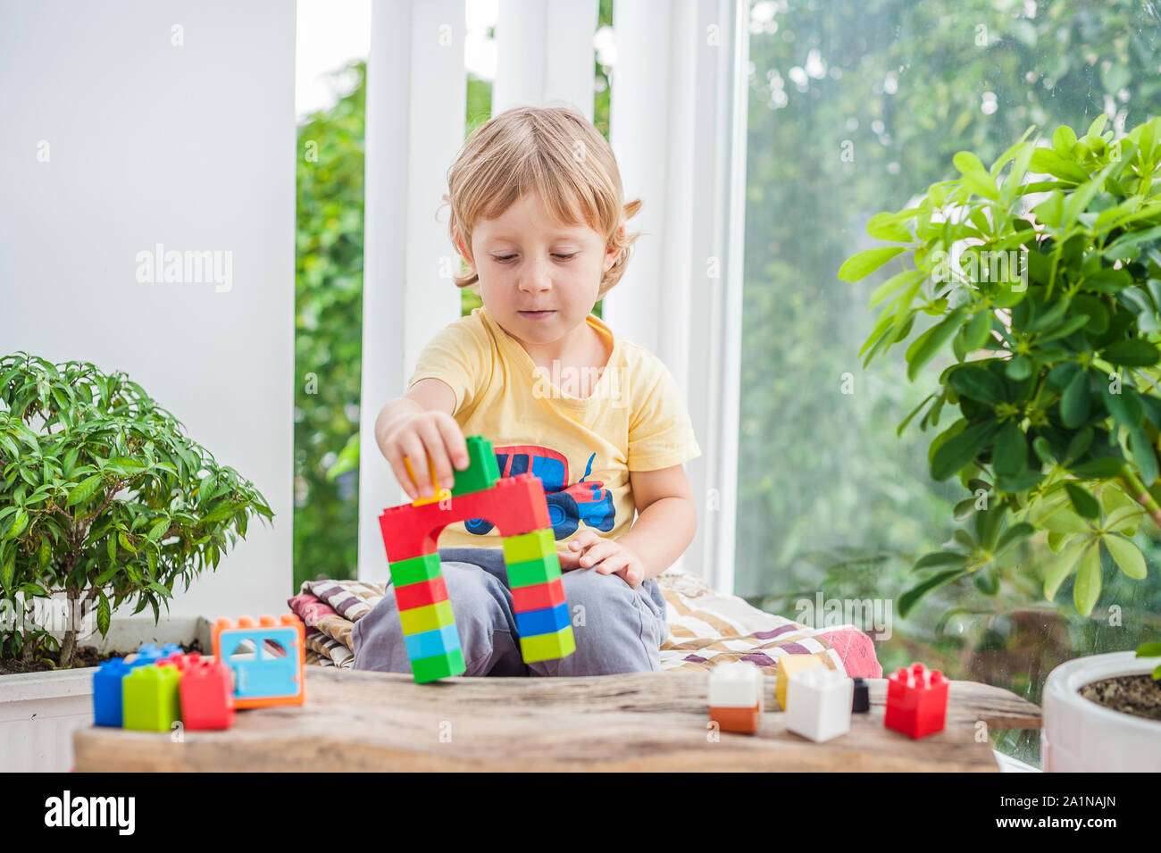 Cute little kid boy with playing with lots of colorful plastic blocks ...