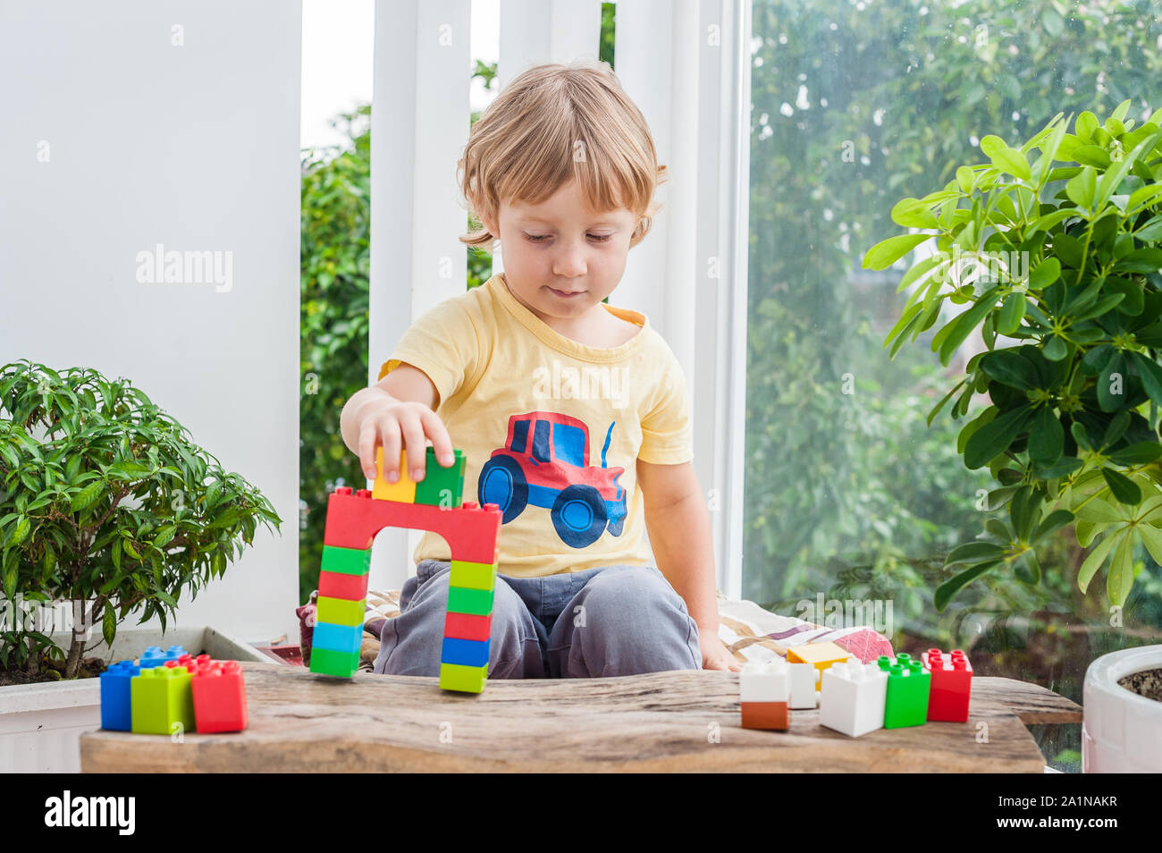 Cute little kid boy with playing with lots of colorful plastic blocks ...