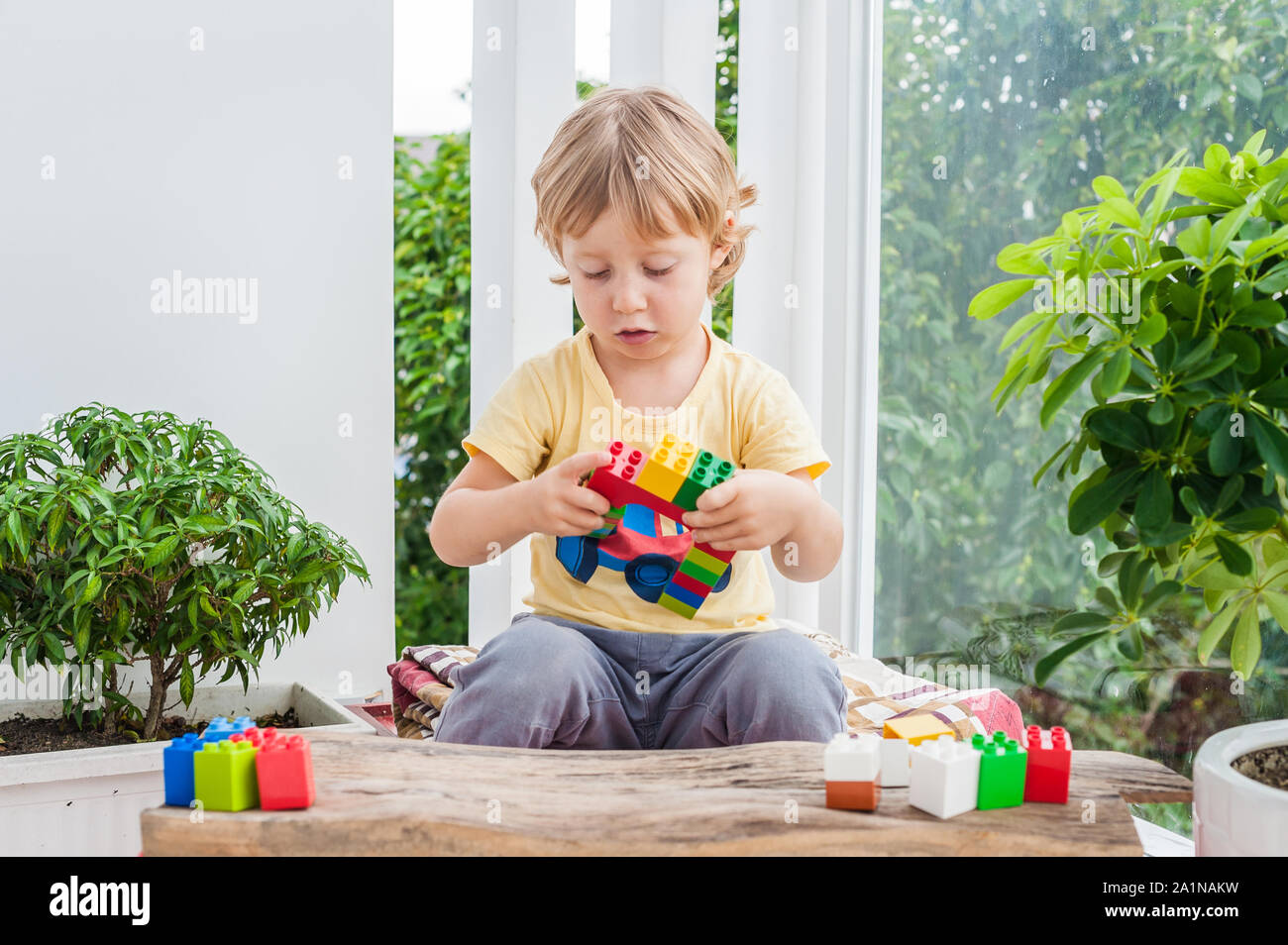 Cute little kid boy with playing with lots of colorful plastic blocks ...