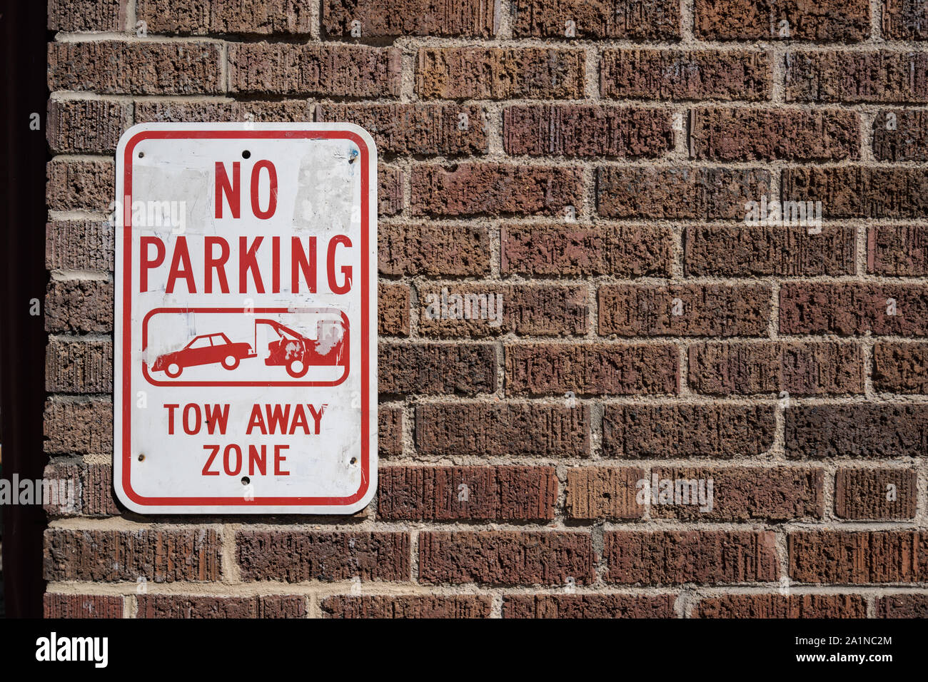 No Parking Sign on a Brick Wall. Tow away zone Stock Photo