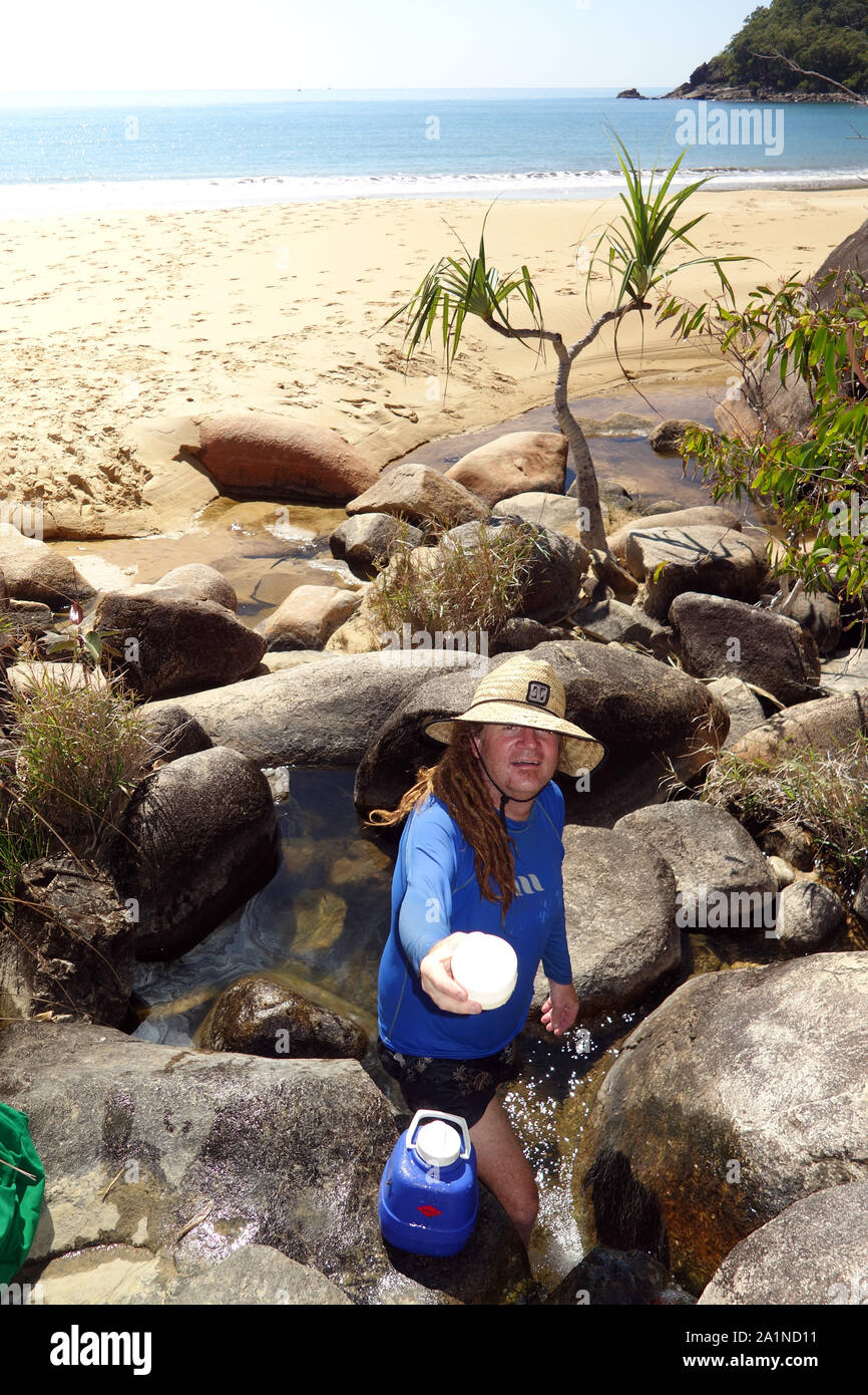 Offering a cup of water from the fresh water stream at Turtle Bay, Cape Grafton, near Cairns, Queensland, Australia. No MR or PR Stock Photo