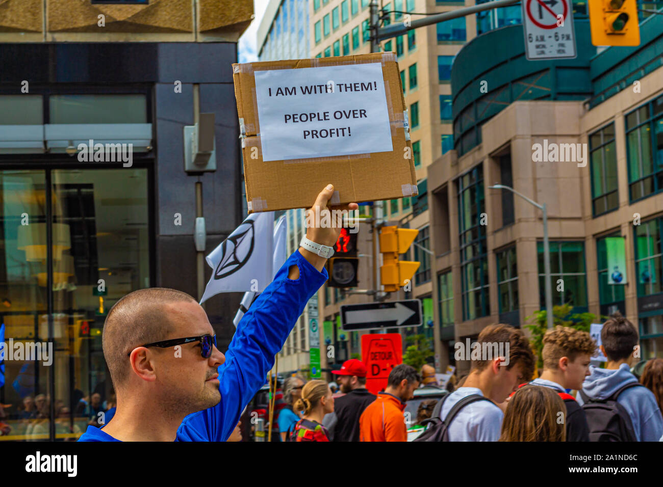 A man joins in the crowd protesting inaction on climate change during a Climate Strike event in Ottawa, holding a sign reading 'People Over Profit'. Stock Photo