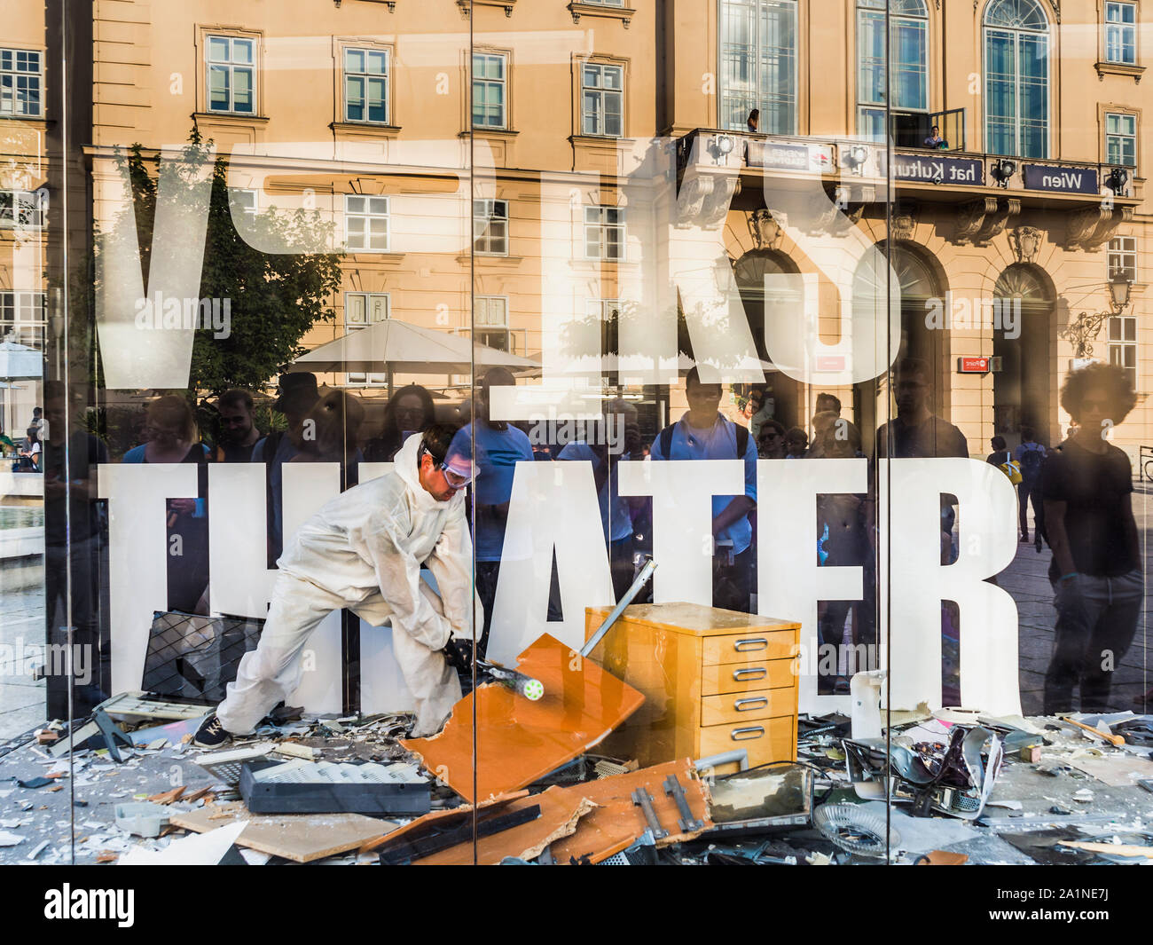 'Volks Theater' (People's Theatre) performer smashing computer equipment in large glass cubicle in Museum Quarter - Vienna, Austria. Stock Photo