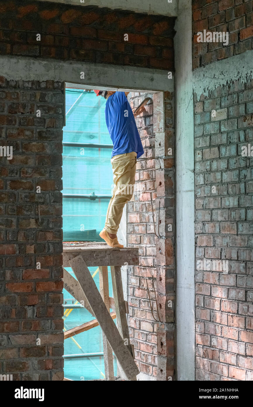 plasterer making up a brick wall vertical composition Stock Photo