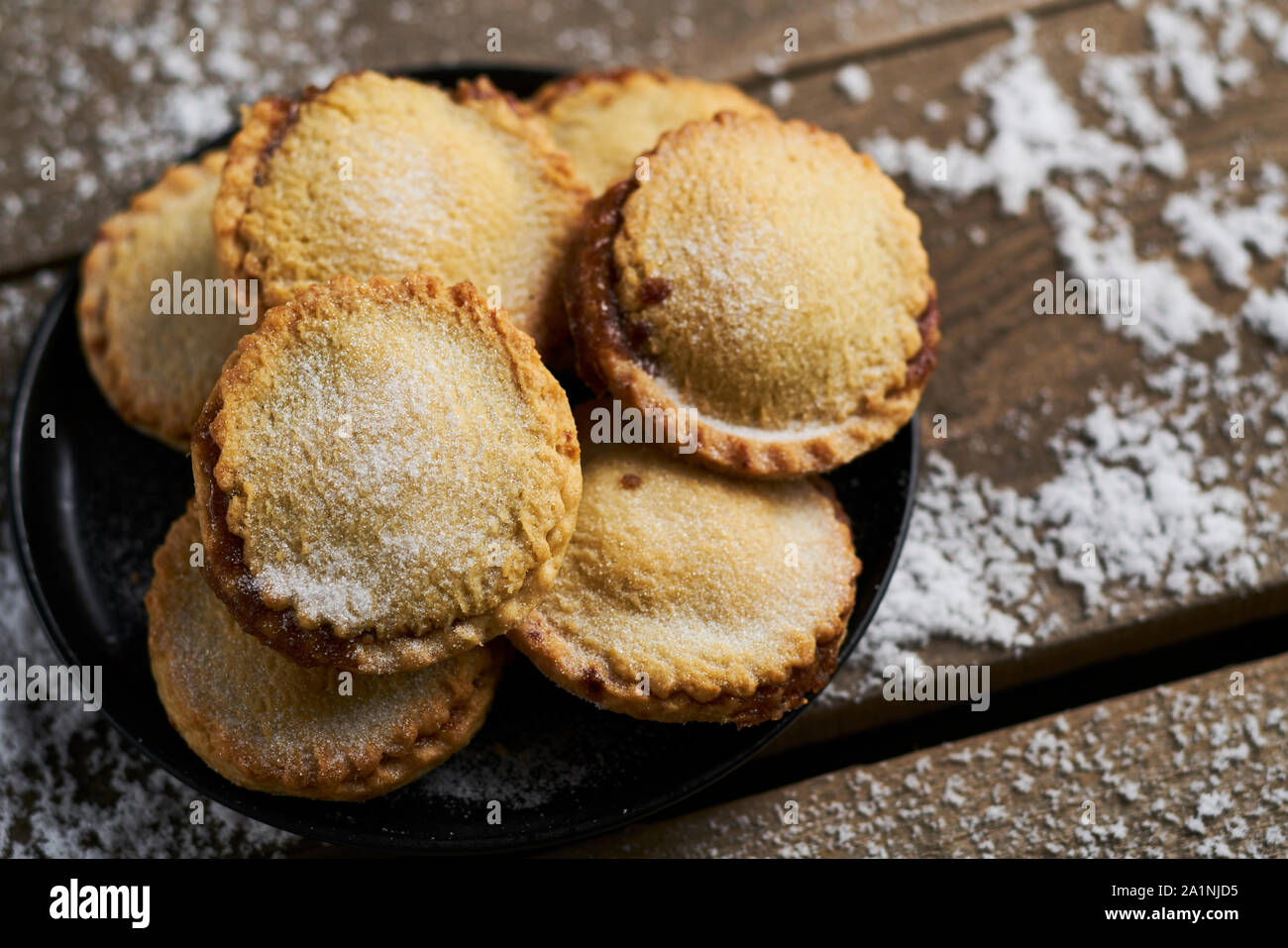 Plate of shortcrust pastry mince pies on a rustic wooden table with ...