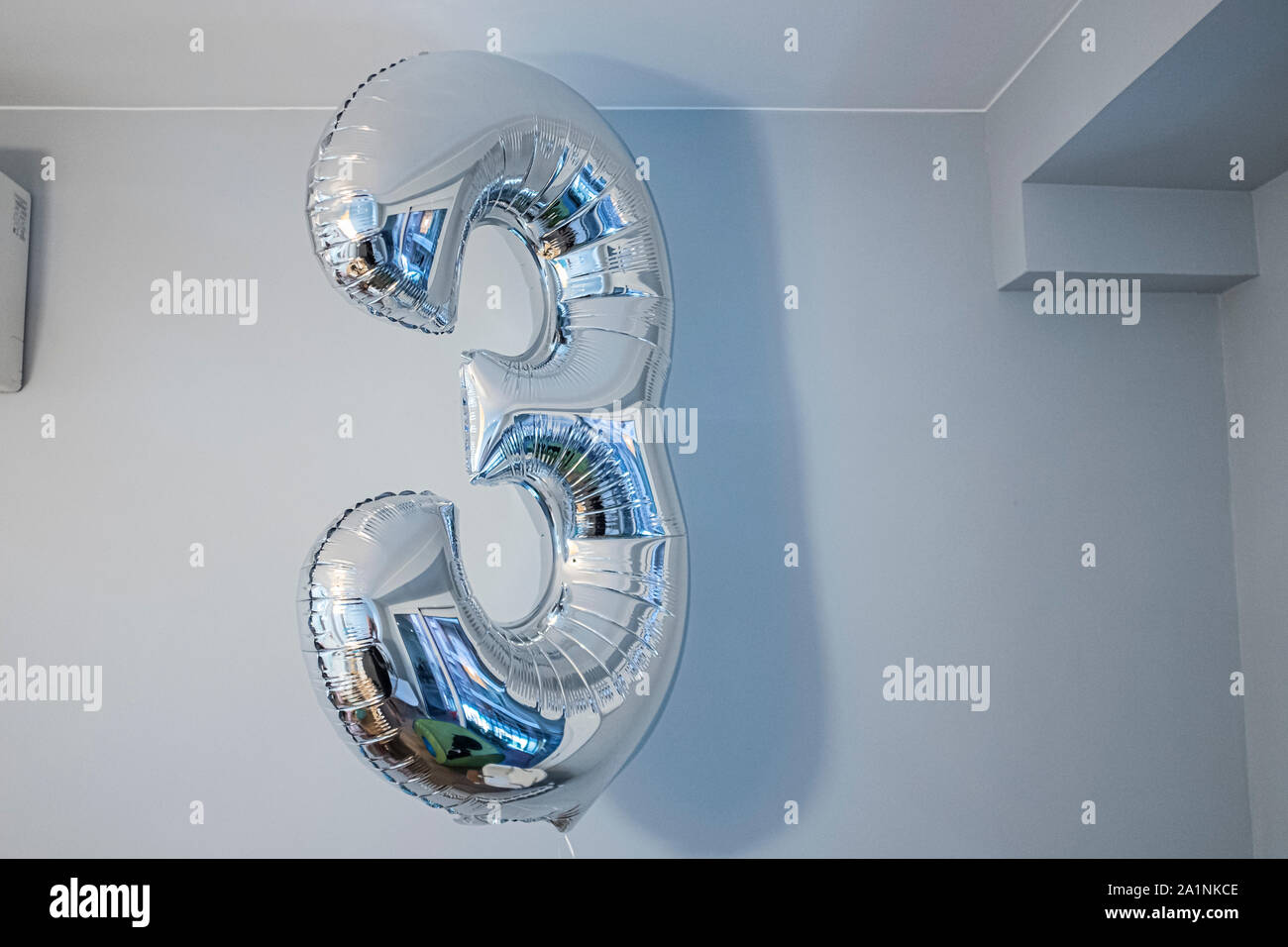Silver number three balloon inflated on an indoor home scene Stock Photo