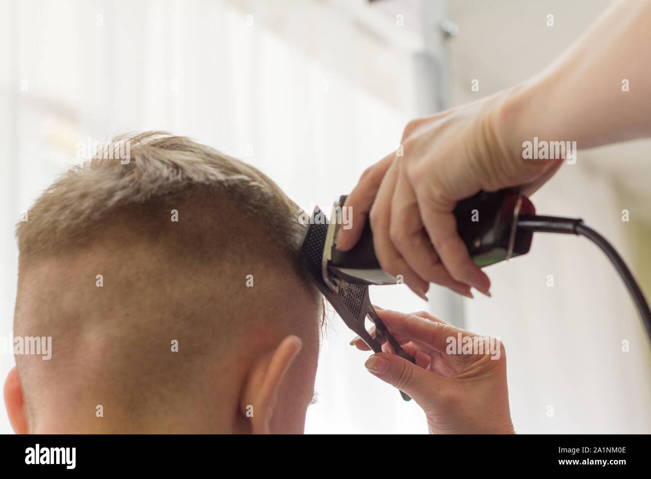 the Barber cutting the boy trimmer head teen almost bald Stock Photo