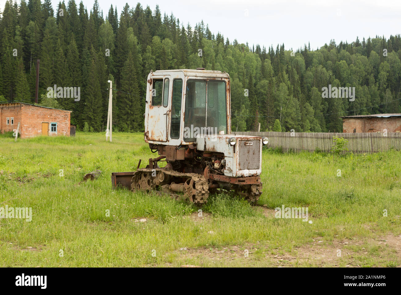 Old tractor on a field in the village Stock Photo - Alamy