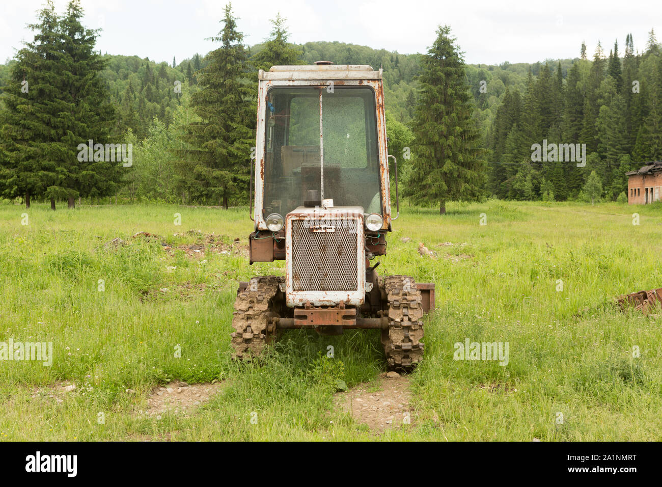 Old tractor on a field in the village Stock Photo - Alamy
