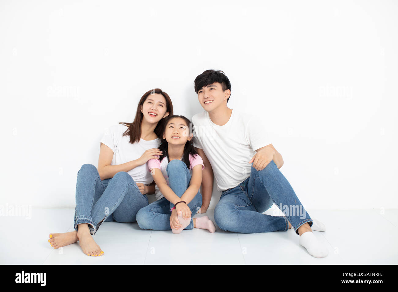 Happy Young family Sitting On Floor Looking Up Stock Photo
