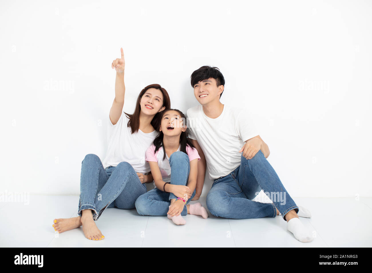 happy young family sitting on floor and looking up Stock Photo
