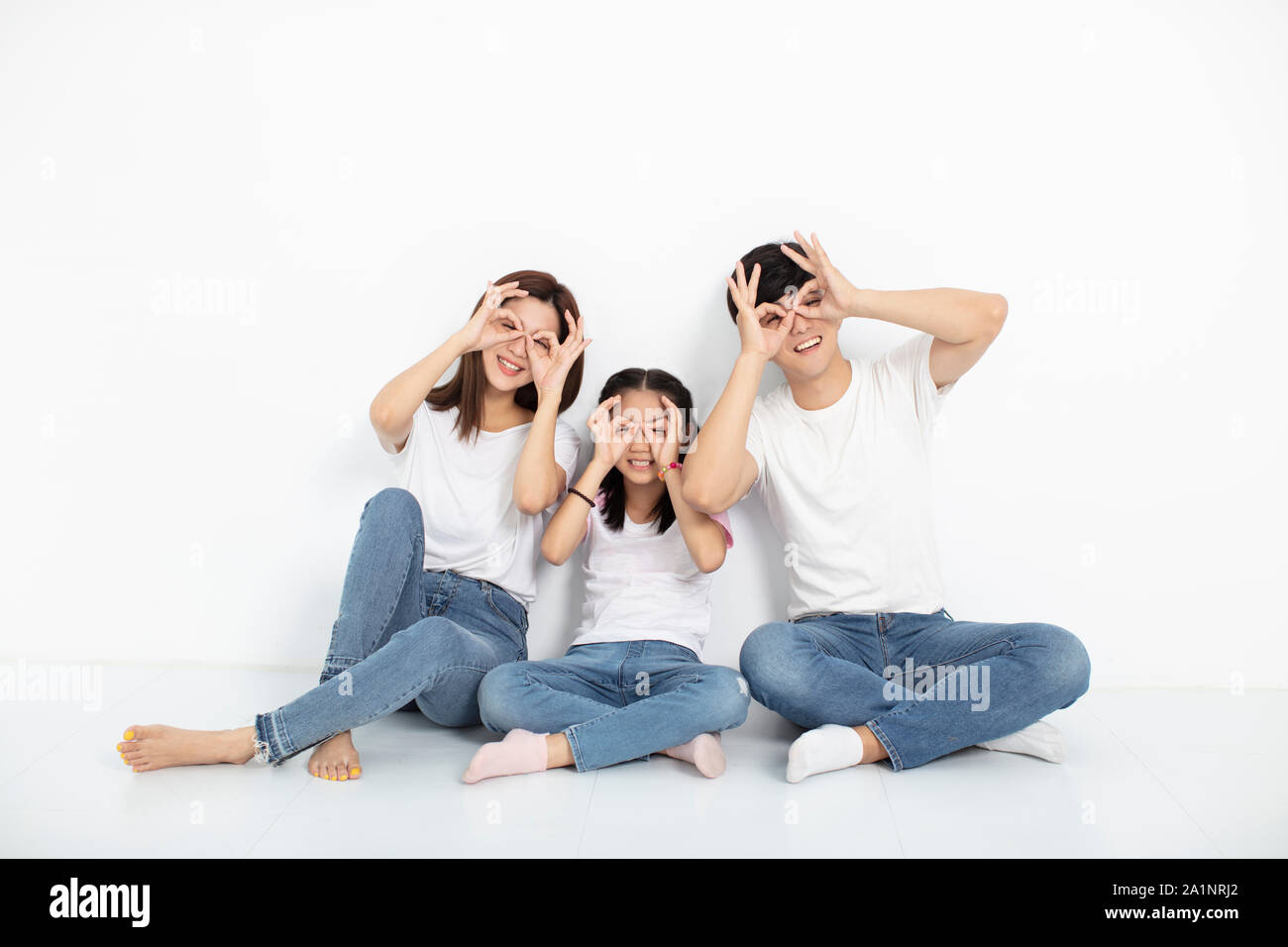 happy young family sitting on floor with looking gesture Stock Photo