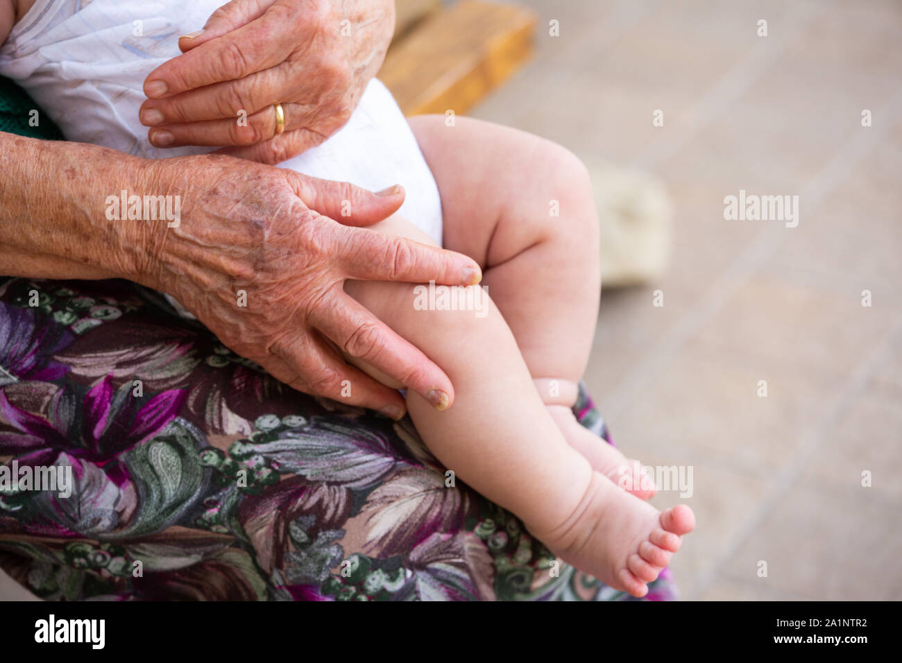 An elderly woman is holding a small baby a few months old Stock Photo