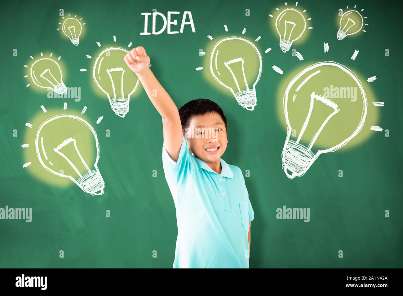 happy asian boy standing against chalkboard with idea bulb concepts Stock Photo