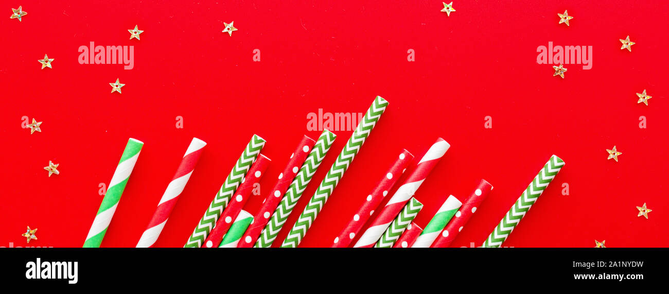 Striped drink straws on red background. Horizontal banner for web. New Year or Xmas pattern. Minimalism concept. Pop art style. Top view, Flat lay Stock Photo