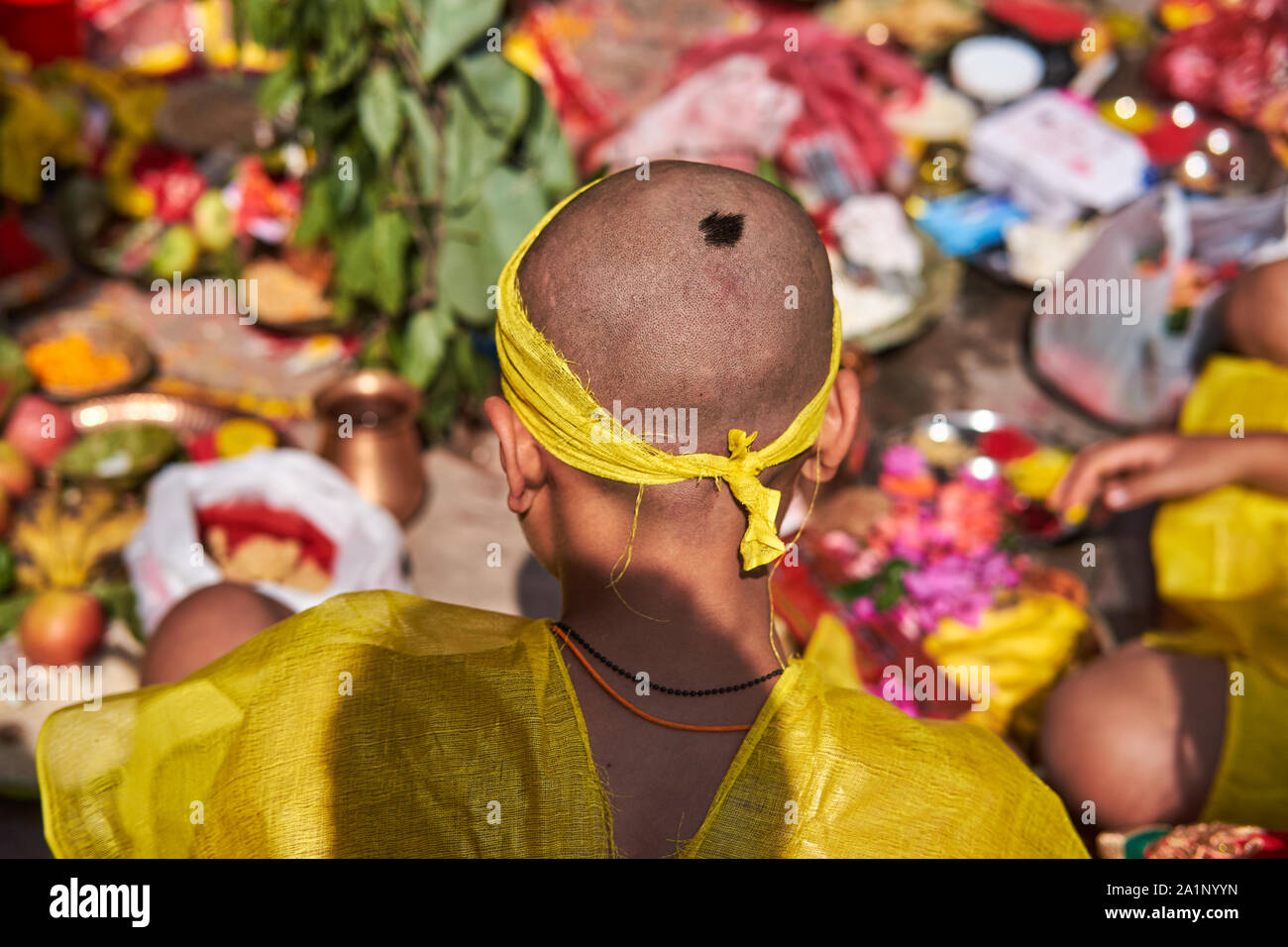A boy in Kathmandu, Nepal, at a Hindu rite with ritually shaved head, only a tuft of hair (shikha, choti) left on the top of the head (head chakra) Stock Photo
