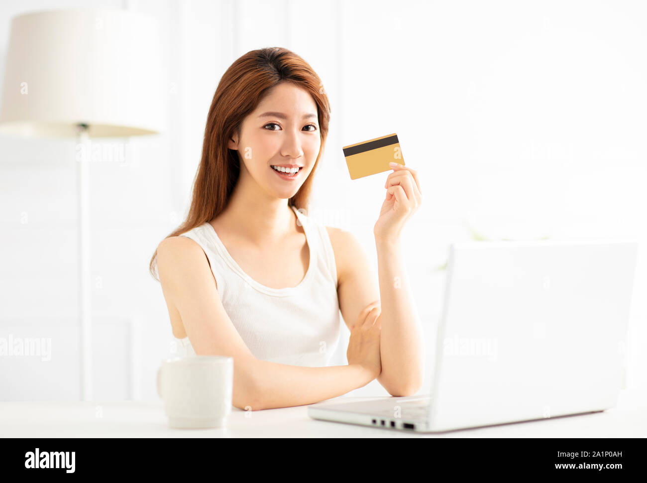 Young woman showing credit card and using laptop Stock Photo