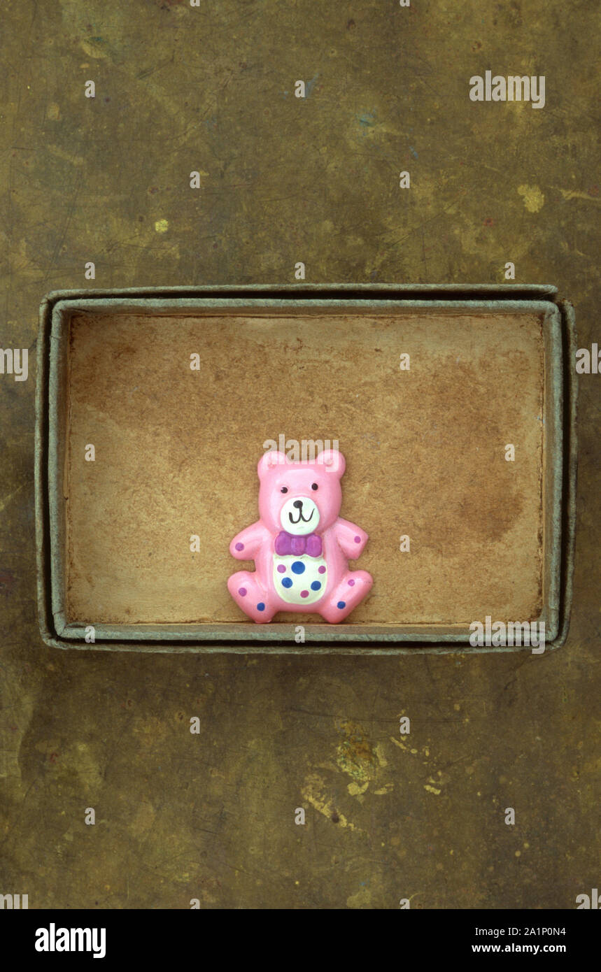 Cardboard tray containing small plastic model of pink teddy bear with white stomach and red bow tie Stock Photo