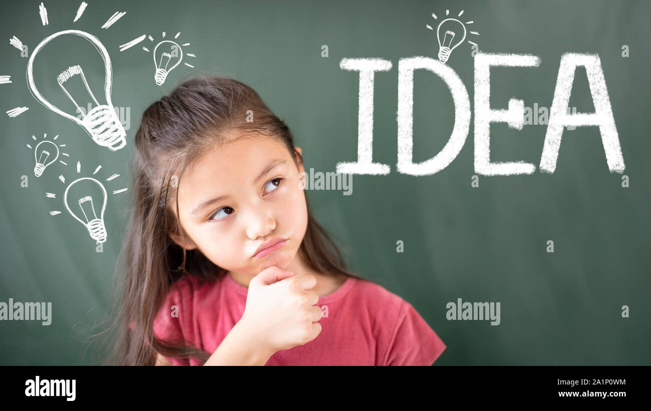 little girl standing against chalkboard and idea bulb concept Stock Photo