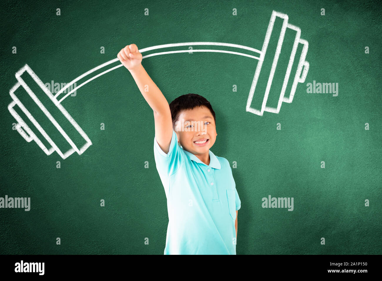 kid standing against chalkboard with strong winner concept Stock Photo